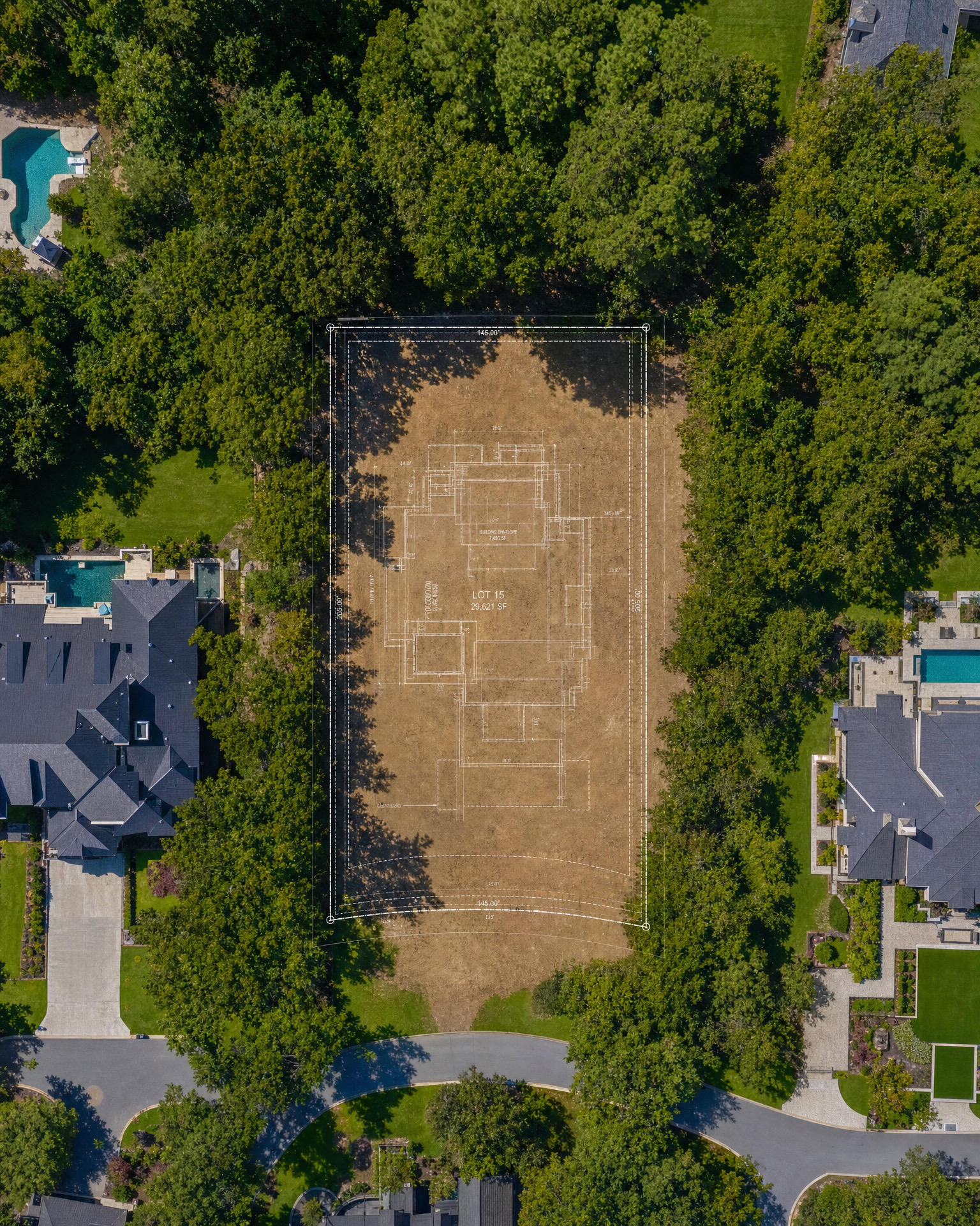 Aerial view of a cleared parcel with a blueprint overlay, surrounded by lush trees and luxury homes